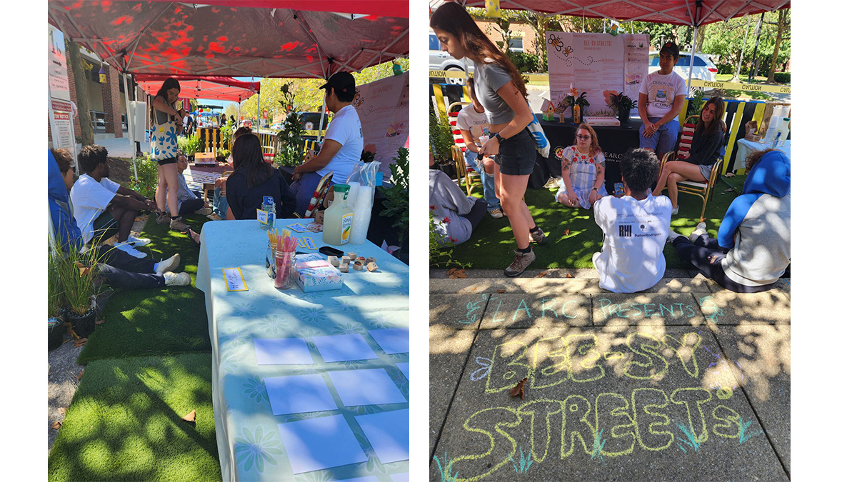 People at a booth and others sitting by a chalk sign on the ground that reads: Bee-sy Streets