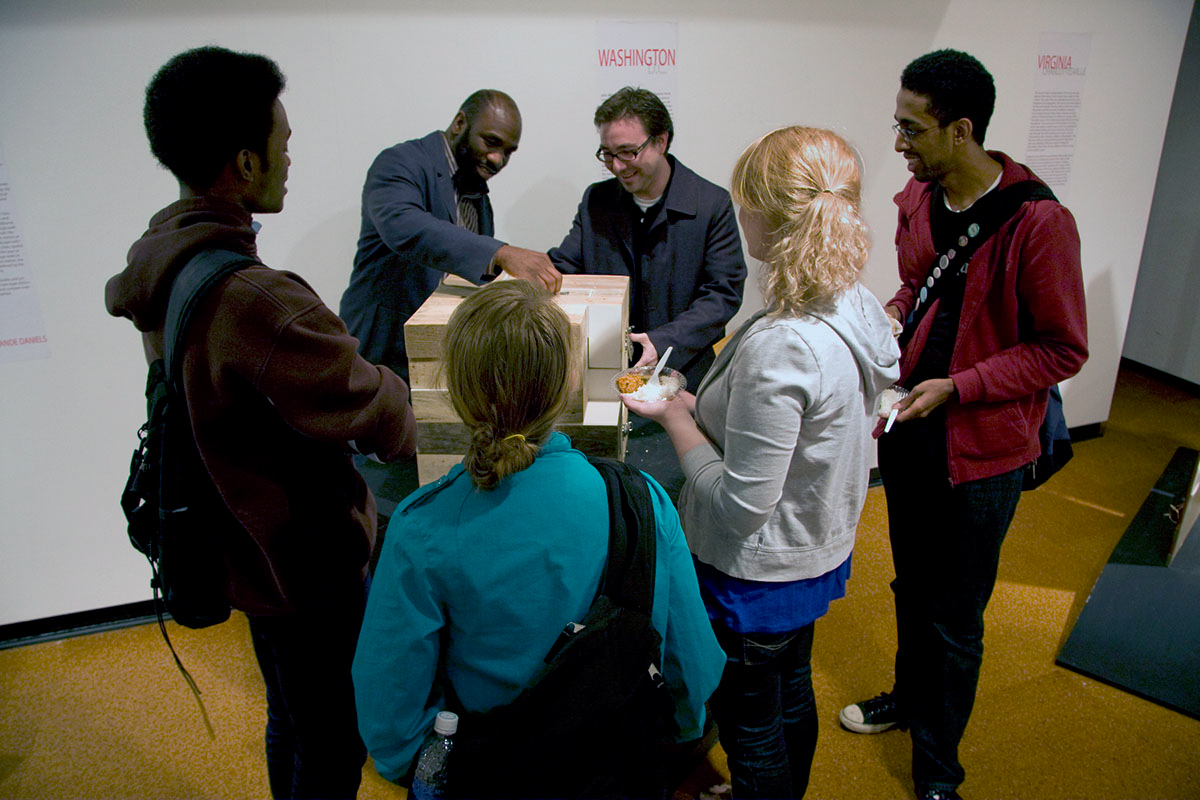 People looking at a wooden box, which was the "Dresser Trunk Project"