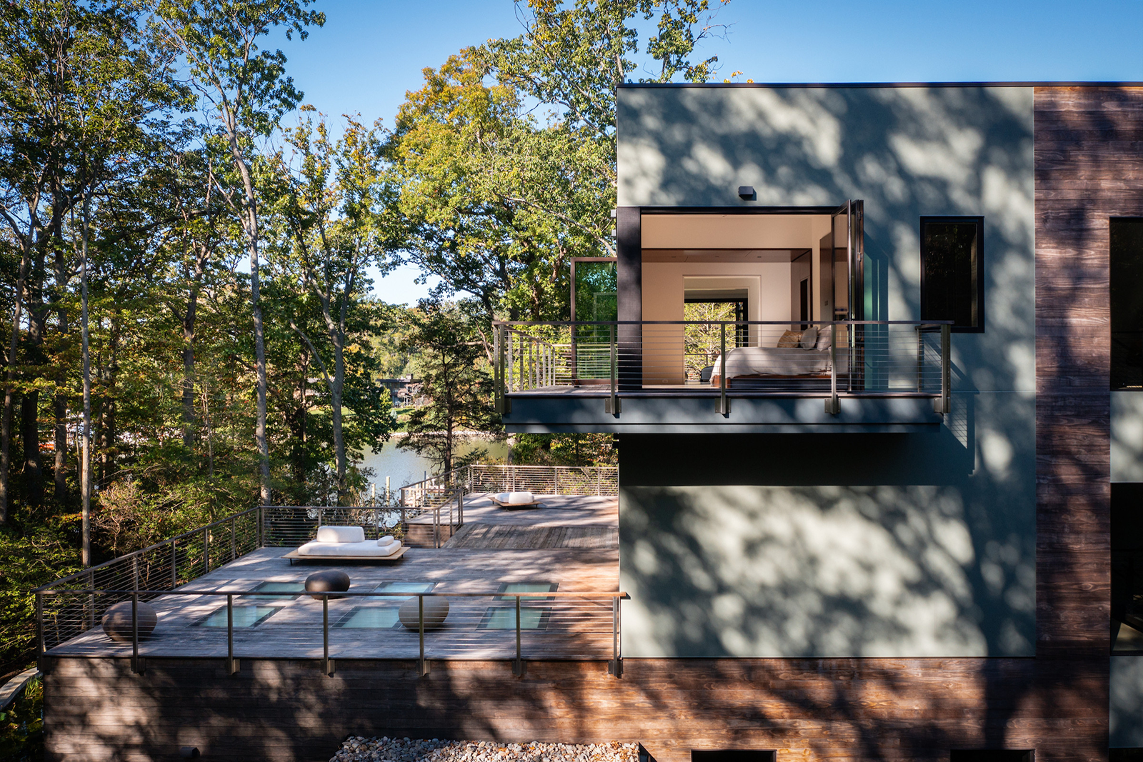 A home by the lake with a large deck looking into the forest.