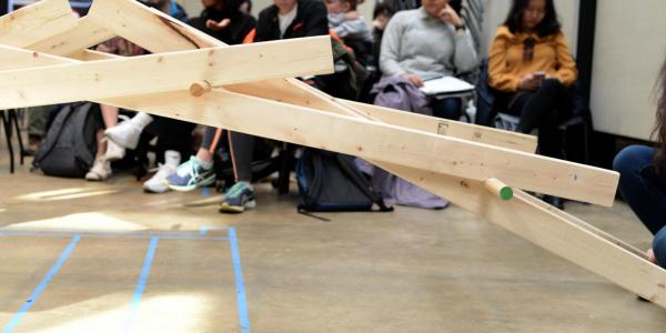 Wooden bridge structure; students in background.