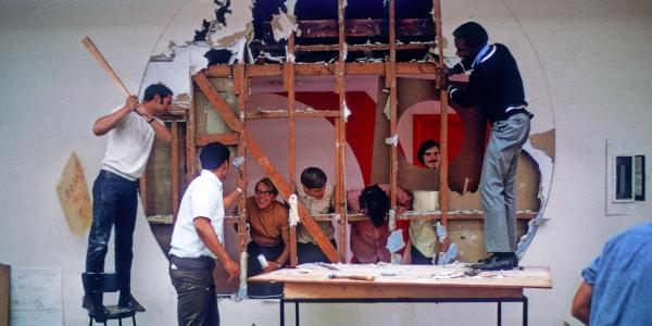 Students from class of '72 standing by a large hole in the wall.