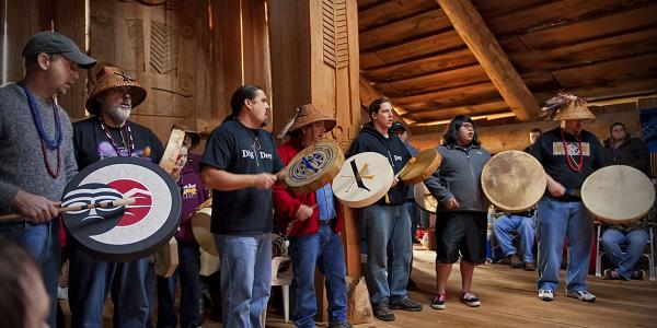 Chinook People playing instruments at plankhouse.