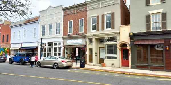 Housing and retail on a main street with cars in front