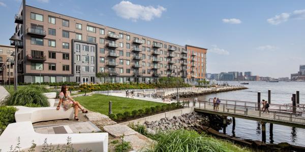 Residential development by the water, a woman is sitting on a bench looking at the water