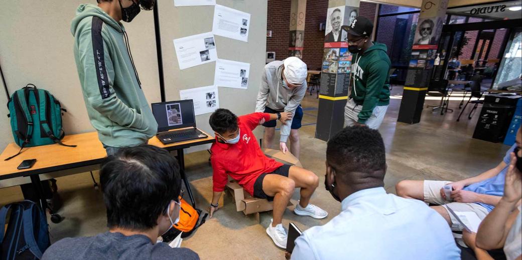 Student testing a cardboard chair