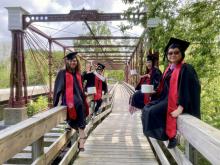 HISP Graduates on the historic Bollman Iron Truss Bridge, holding toilet paper.