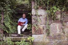 Willie Graham reading a book on a stone staircase.