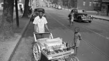 Young boy by a snowball vendor in 1940s Harlem Park. 