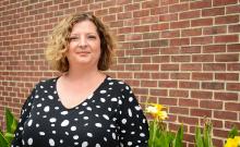 Dawn Jourdan with yellow flowers and brick building in the background