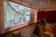 People sitting on wooden cubes and talking while a projection shows the Dupont underground