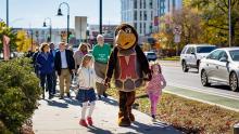 Testudo mascot walking with children on a sidewalk. 