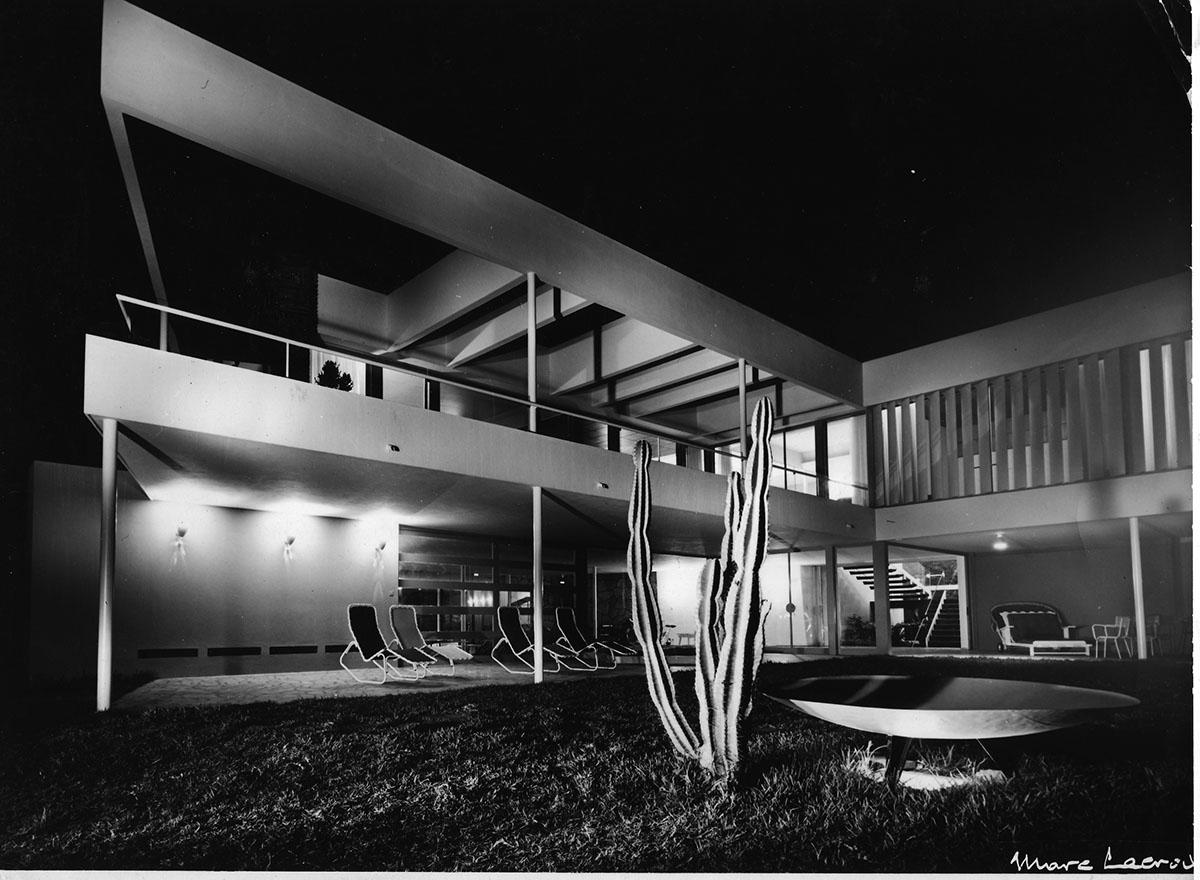 Black and white photo of Varsano Villa in Casablanca. A cactus in in the foreground and reclining chairs are on the patio.