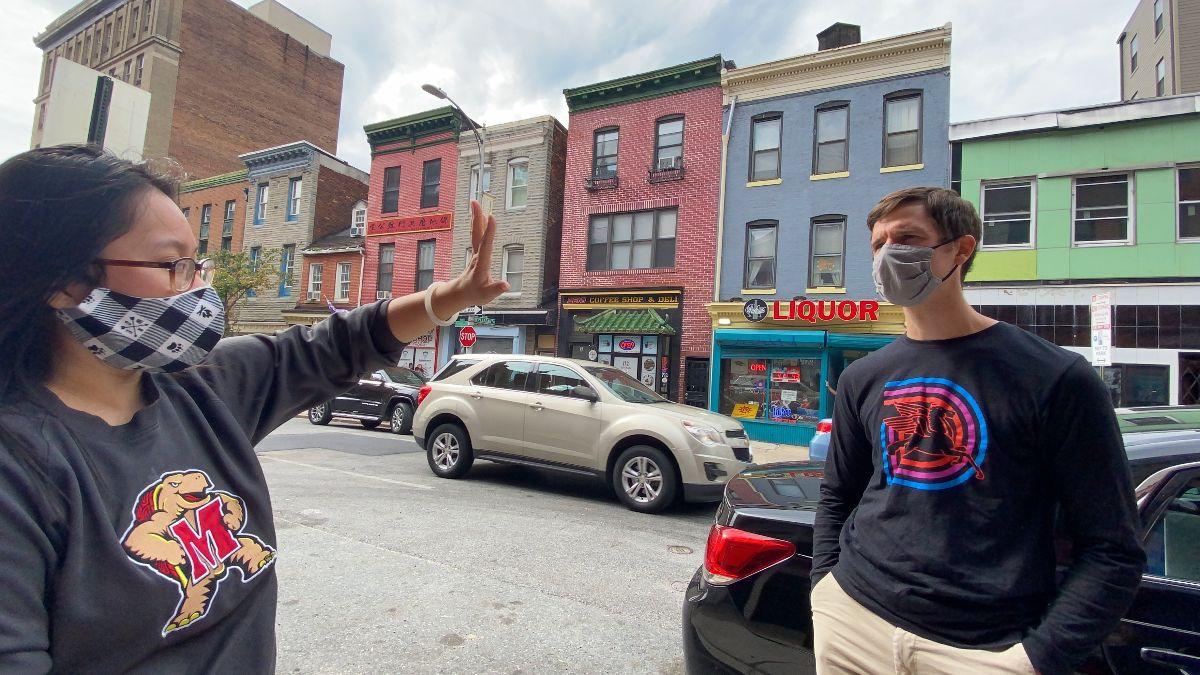 Karen Yee gesturing to someone. Both are outside and wearing masks.