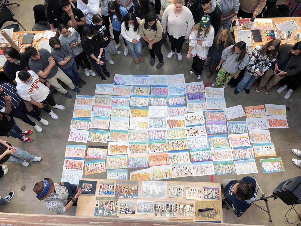 Students standing around multiple Lucien Steil style drawings of buildings, in the Great Space. 