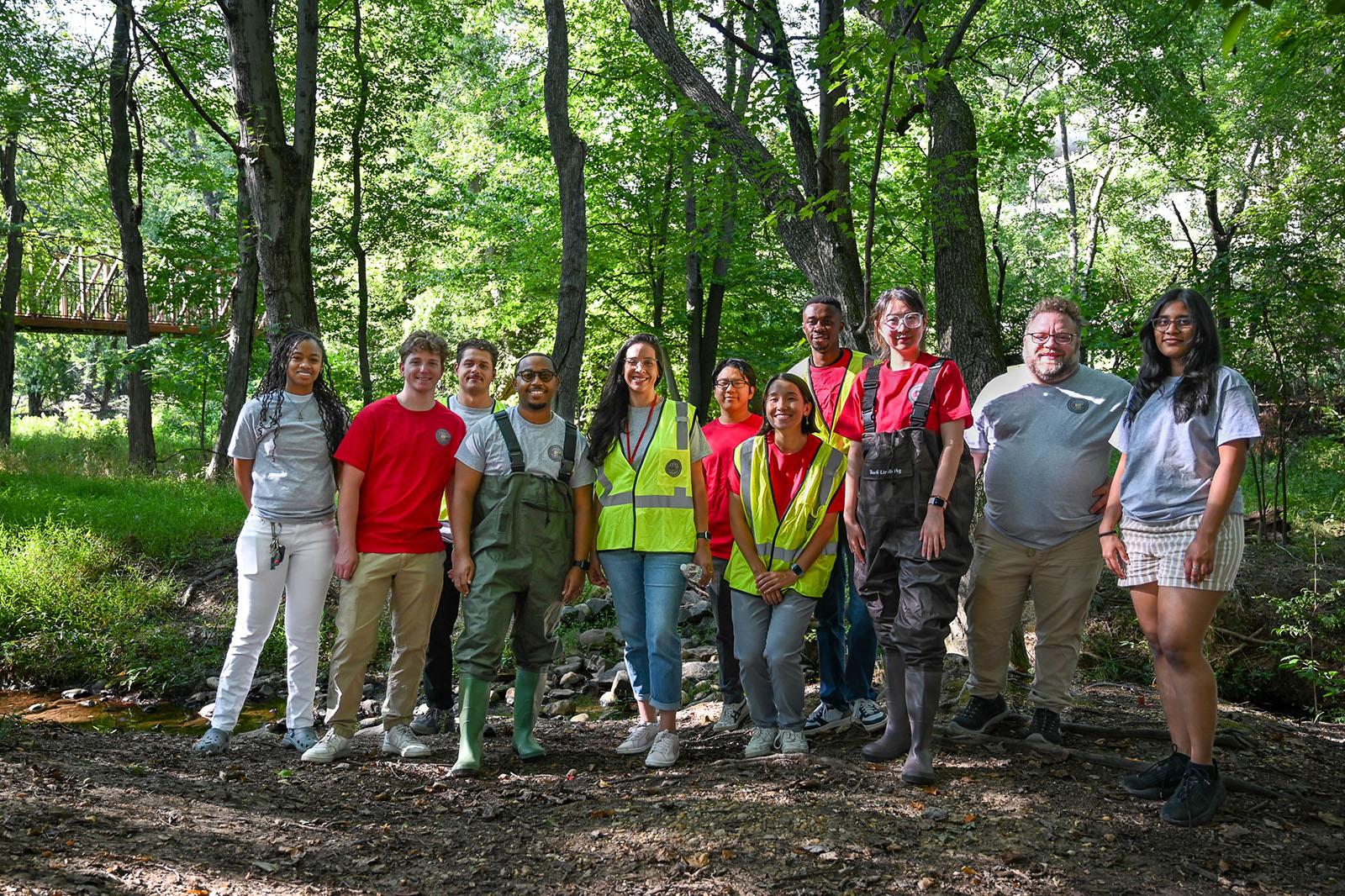 SIRJ Lab team members on a site visit, green trees and a bridge in the background