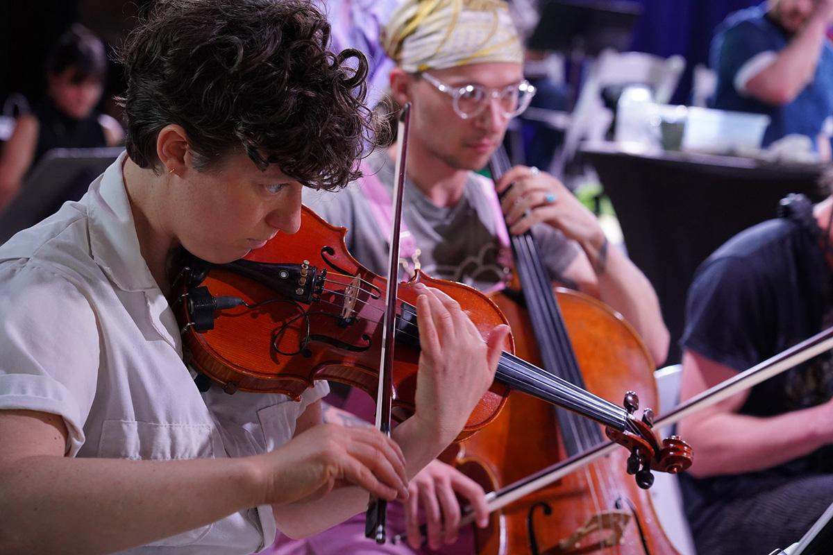 A person playing the violin and another the cello in the background